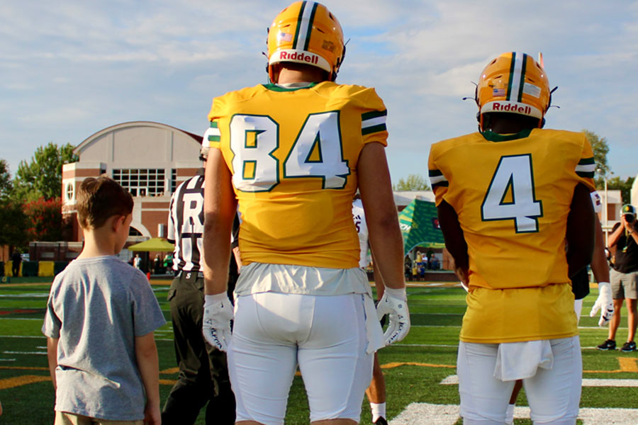 Football players on the field standing next to a child